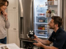 Appliance repair technician explaining a refrigerator repair to an Alpharetta homeowner in a modern kitchen, highlighting the cost savings of repairing instead of replacing a broken appliance.